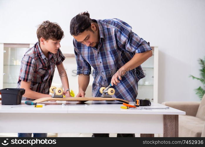 Young father repairing skateboard with his son at home