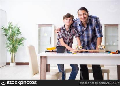 Young father repairing skateboard with his son at home