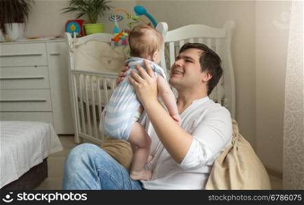 Young father sitting in bag chair and holding his little baby son