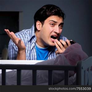 Young father under stress due to baby crying at night. The young father under stress due to baby crying at night