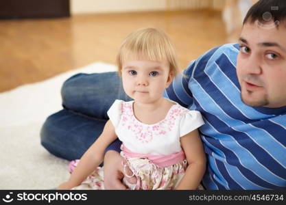 young father with a daughter at home in the living-room