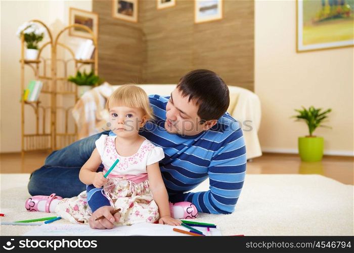 young father with a daughter at home in the living-room