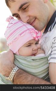 Young father with his daughter in sling, spring outdoor