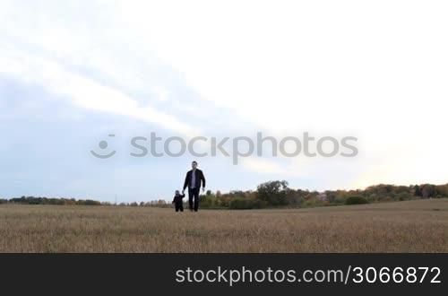Young father with his son walking in the field.