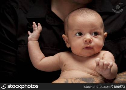 Young Father with Tattoo Holding His Mixed Race Newborn Baby Under Dramatic Lighting.