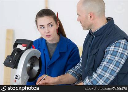 young female apprentice being introduced to a circular saw