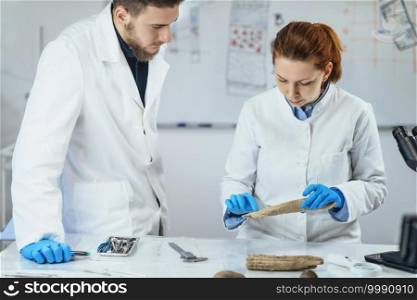 Young female Archaeology researcher in laboratory demonstrates how antler was used as tool in prehistory.  . Archaeology Researchers Analyzing Ancient Antler Tool in Laboratory