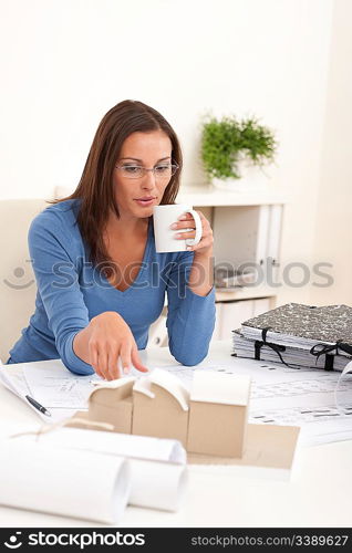 Young female architect holding cup of coffee at the office