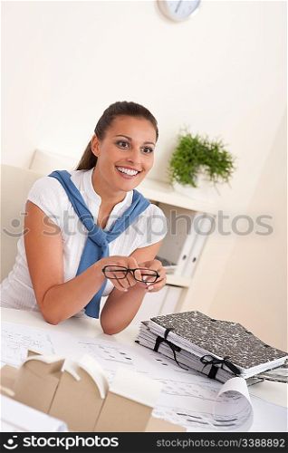 Young female architect sitting at the office holding glasses