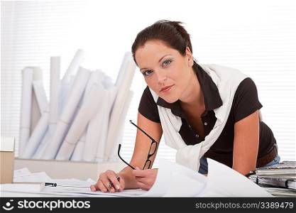Young female architect with plans at the office holding glasses