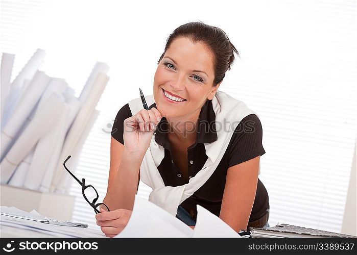 Young female architect with plans at the office holding glasses