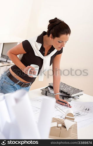 Young female architect working and drinking coffee at the office