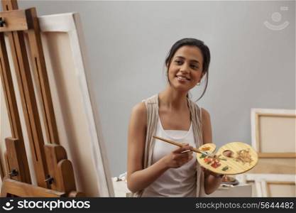 Young female artist painting on canvas