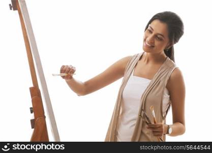 Young female artist painting on canvas isolated over white background