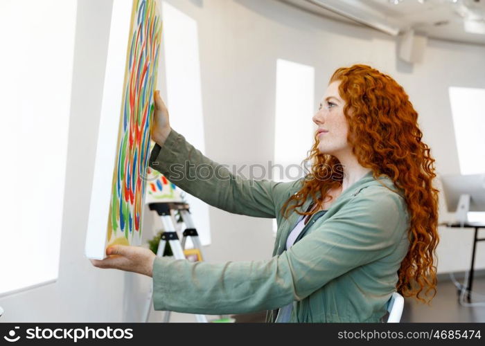 Young female artist with her picture. Young female artist in gallery with her picture