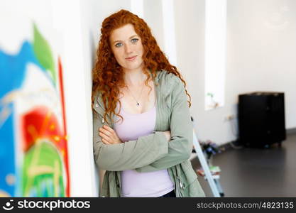 Young female artist with her picture. Young female artist in gallery with her picture