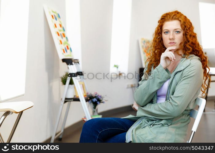 Young female artist with her picture. Young female artist in gallery with her picture