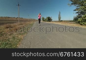 Young female athlete runner jogging during outdoor workout on the road wide angle