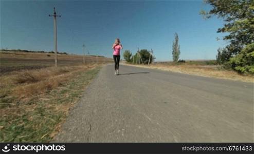 Young female athlete runner jogging during outdoor workout on the road wide angle