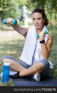 young female athlete seated exercising with dumbbells