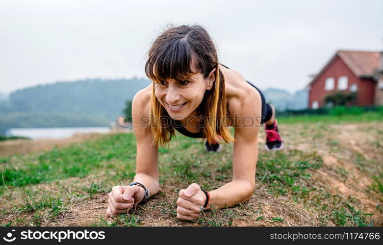 Young female athlete training doing plank outdoors. Female athlete training doing plank