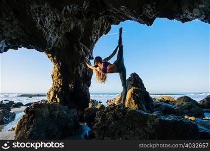 Young female ballet dancer poised on one leg in sea cave, Los Angeles, California, USA