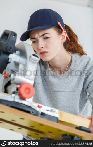 young female carpenter cutting wood with tablesaw in workshop
