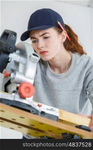 young female carpenter cutting wood with tablesaw in workshop