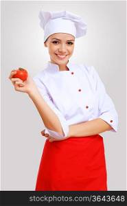 Young female chef in red apron against grey background