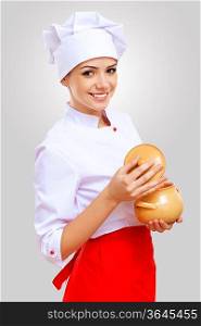 Young female chef in red apron against grey background