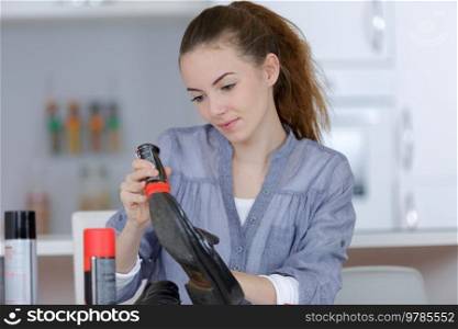 young female cleaning black shoes