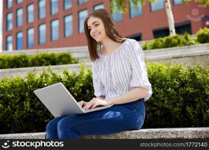 Young Female College Student With Laptop Working Outdoors On College Campus