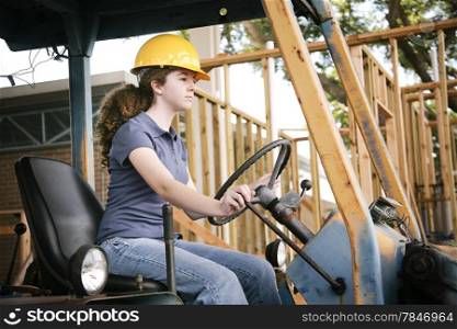 Young female construction apprentice learning to drive heavy equipment.