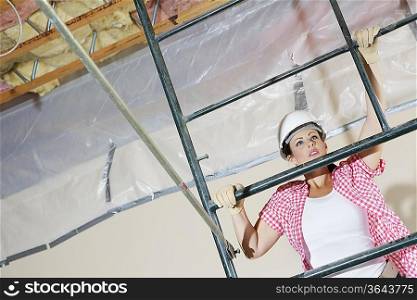Young female construction worker climbing on scaffold