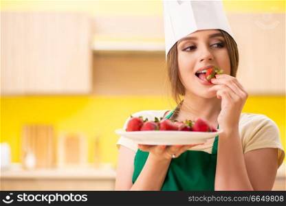 Young female cook eating strawberries