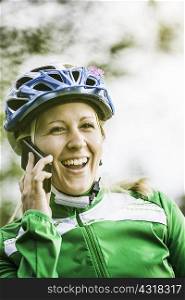 Young female cyclist laughing and chatting on smartphone, Augsburg, Bavaria, Germany