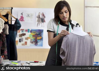 Young female designer fixing dress on mannequin
