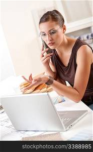 Young female designer on the phone at office with laptop and color swatch