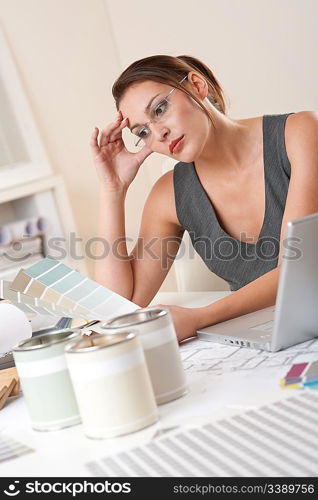 Young female designer working at office with laptop and color swatch