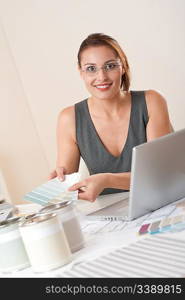 Young female designer working at office with laptop and color swatch