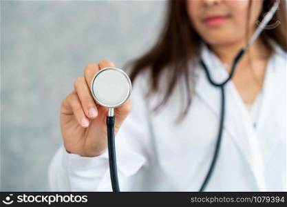 Young female doctor at hospital pointing stethoscope at blank space. Selective focus at doctors hand. Medical healthcare concept.