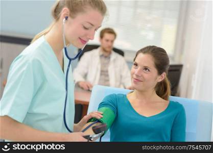 young female doctor checking blood pressure of patient