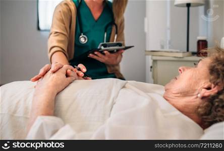 Young female doctor comforting older female patient. Female doctor comforting older patient