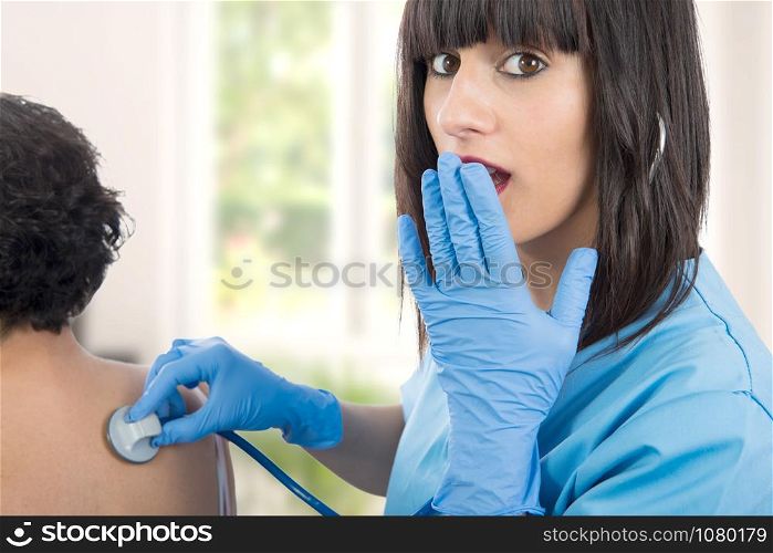 young female doctor examines a patient with a stethoscope