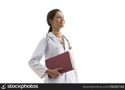 Young female doctor holding book while looking away isolated over white background
