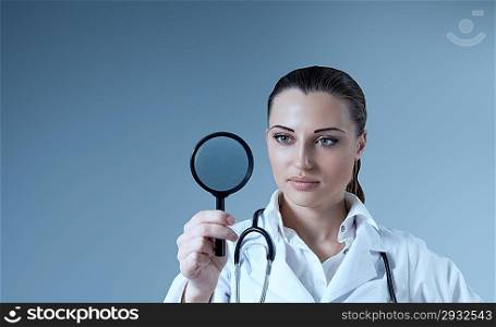 Young female doctor holding magnifying glass in right hand. Empty space to place your logo / text / product. Medical / pharmaceutical research concept. Healthcare collection.