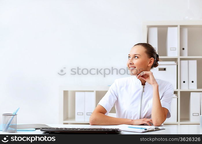 Young female doctor in white uniform at workplace