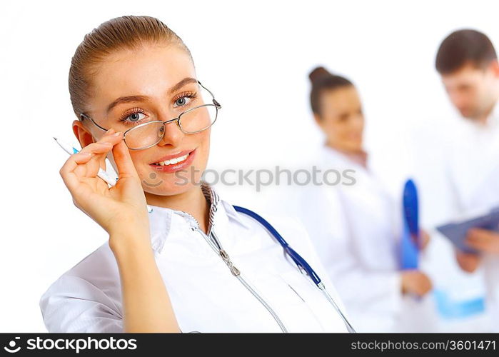 Young female doctor in white uniform with collegues on the background