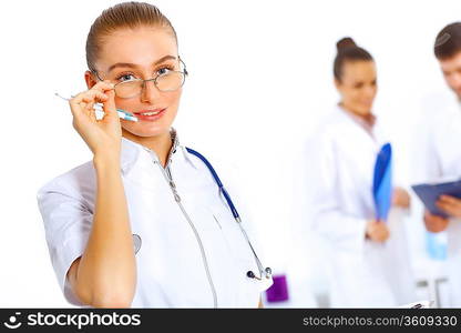 Young female doctor in white uniform with collegues on the background