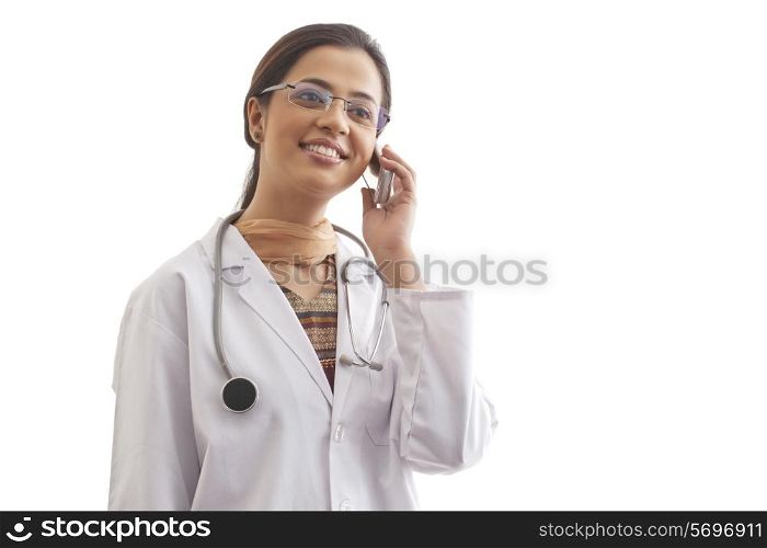 Young female doctor looking away while on call against white background